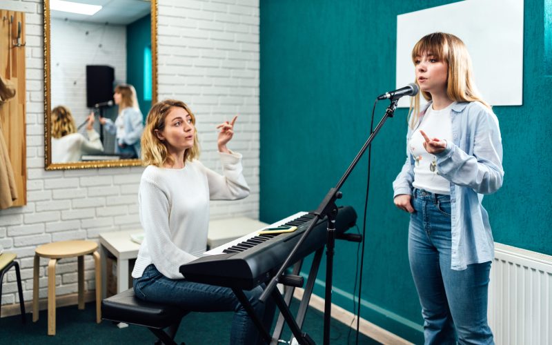Vocal teacher showing her student how to sing in the microphone