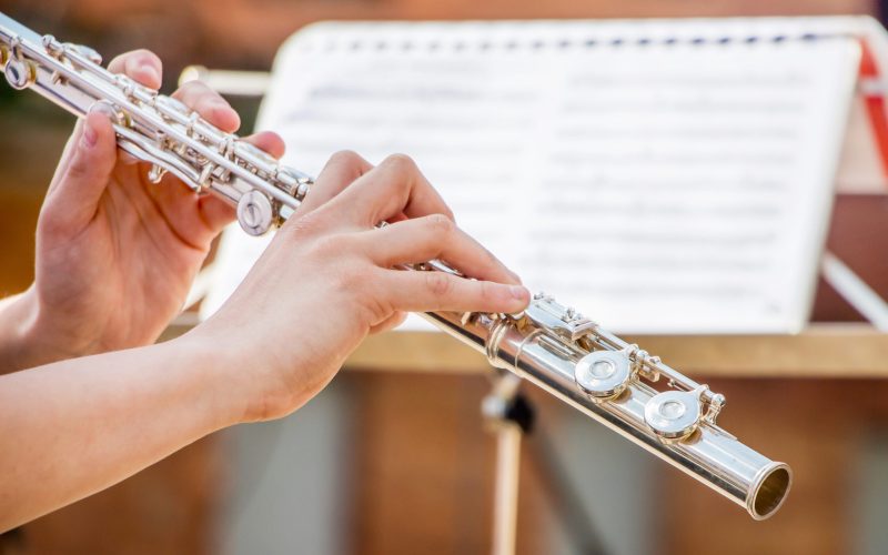 The girl plays the flute. Flute in the hands of the musician during the performance of the musical play