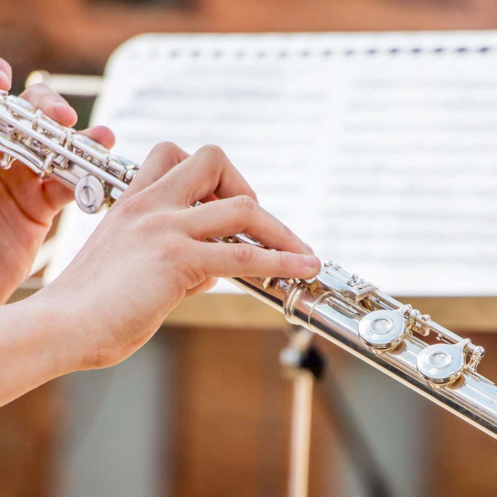 The girl plays the flute. Flute in the hands of the musician during the performance of the musical play